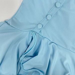 Detail view of light blue dress showing three covered buttons and ruffled edge textures