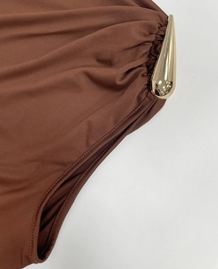 Detail aus braunem Stoff mit eleganter goldener Tropfenschnalle und Raffungen