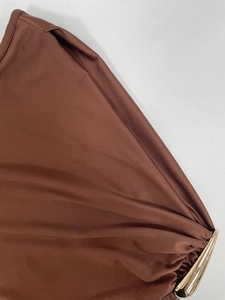 Detail eines braunen ärmellosen Kleides mit goldener Metallschnalle und eleganten Falten