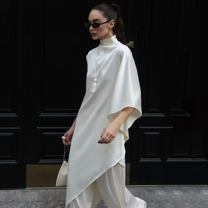 Détail de l'ensemble en satin blanc avec chemisier asymétrique et pantalon large fluide