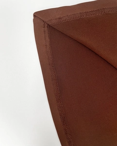 Nahaufnahme von dunkelbraunem Stoff mit präzisen Nähten und gewebter Textur am Kleid