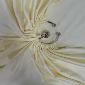 Détail de la boucle en métal argenté et plis sur le tissu de robe soyeux jaune pâle