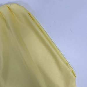 Détail d'une robe jaune élégante montrant la boucle métallique et la texture plissée