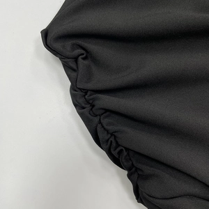 Détail macro d'une robe noire élégante avec coutures froncées et texture tricotée