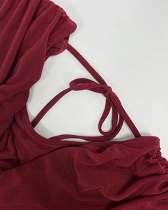 Close-up of wine red ribbed knit fabric detail and elegant bow ribbon on the dress