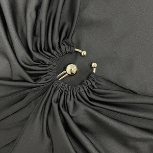 Détail d'une robe noire présentant une découpe circulaire et boucle en métal doré