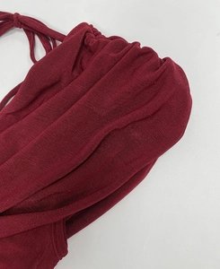 Macro shot of burgundy ruched fabric texture and drawstring details on an elegant dress