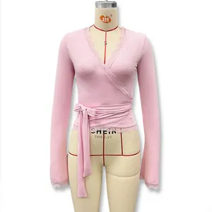 Détail du haut cache-cœur rose avec bordure en dentelle au col en V et nœud à la taille