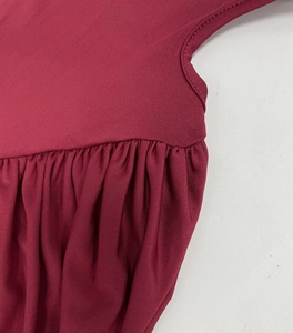 Detail shot of elegant pleated waist design and stitching on burgundy long sleeve dress