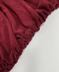 Close-up of wine red ribbed knit fabric with elegant ruched details and fine vertical textures