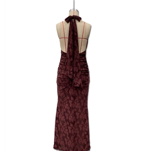 Detail of burgundy lace backless dress featuring a large ribbon bow and floral pattern