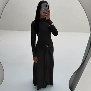 Détail d'une robe noire à manches longues avec anneau doré et plis drapés sur la taille