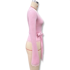 Détail d'un haut rose à manches longues avec bordure en dentelle et nœud à la taille