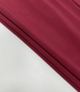 Close-up of wine red ribbed knit fabric texture on a long sleeve slim dress