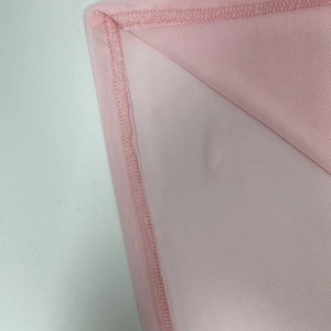 Dettaglio ravvicinato del tessuto a rete rosa con cuciture overlock professionali sull'abito