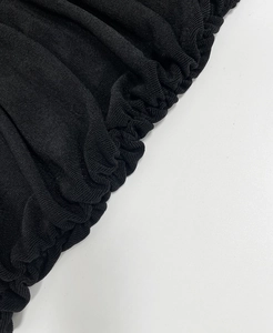 Detailed close-up of black knitted fabric with elegant ruched and shirring textures
