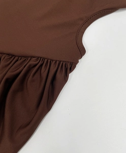 Detailed close-up of dark brown ruched fabric seams and pleated edge on elegant dress