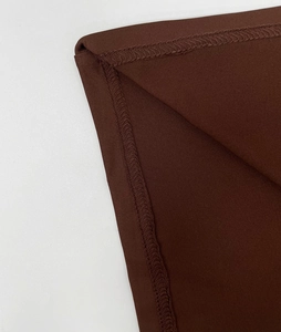 Detailed view of the overlock stitch craftsmanship on the dark brown dress fabric