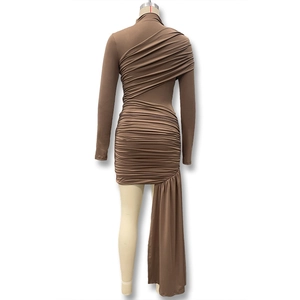 Detail of ruched texture and asymmetrical draping on a slim fit brown long sleeve dress