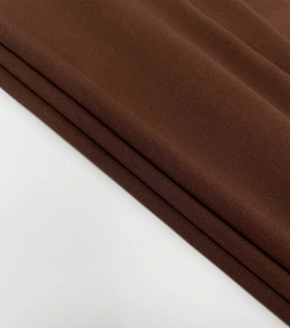 Close-up of dark brown knitted fabric showing elastic ribbed texture and drape