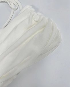 Close-up of ruched white fabric detail and slim shoulder straps on this elegant dress