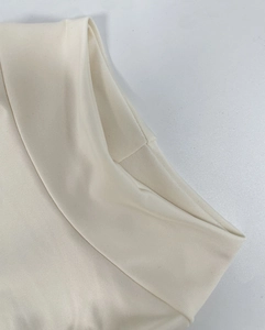 Detail shot of the cream white ribbed knit fabric texture and the neat neckline stitching