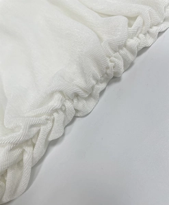 Close-up of ruched white fabric texture and fine stitching on elegant slim fit dress