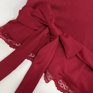 Détail du tissu côtelé bordeaux avec une large ceinture à nœud et bords en dentelle
