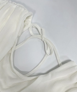 Detailed close-up of white textured fabric featuring elegant bow tie and pleated collar