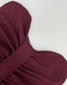 Detail of burgundy knit dress showing elegant cross knot and vertical texture
