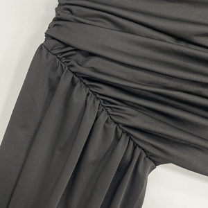 Detail of black slim fit dress featuring ruched fabric with subtle silk sheen texture