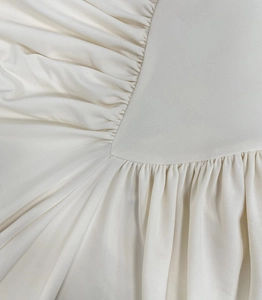 Macro shot of high-density cream fabric with elegant ruched and pleated details