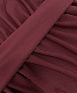 Detailed close-up of burgundy ribbed knit fabric showing rich texture and diagonal draping
