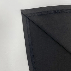 Detailed close-up of the professional overlock stitching on the black bodycon dress hem