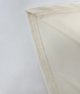 Close-up of the fine stitching and inner edge locking process on a beige slim-fit dress