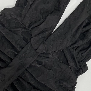 Detailed macro view of black 3D embossed jacquard fabric with elegant pleated cross design