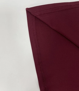 Detail view of precise lockrand stitching and burgundy knit fabric on the dress