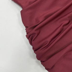 Detail of burgundy ribbed knit fabric showing vertical texture and thick elastic material