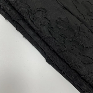 Detailed macro view of black floral jacquard fabric with unique frayed edge texture