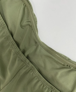 Close-up of olive green dress fabric showing fine twill texture and neat stitching details
