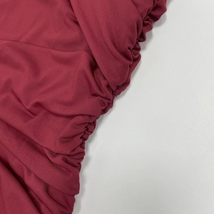 Detailed macro view of burgundy ribbed knit fabric featuring elegant ruched draping texture