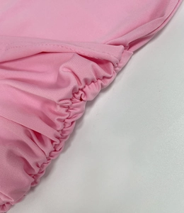 Detailed view of pink knitted fabric with ruched elasticated edge and fine stitching detail