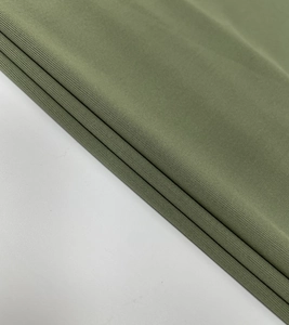 Detailed view of olive green knit fabric texture with elegant folds and soft drape
