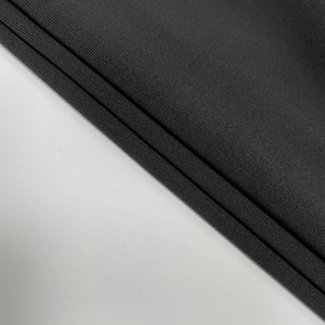 Gros plan détaillé du tissu en maille côtelée noire à haute élasticité et texture mate fine