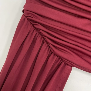 Detail of ruched wine red knit fabric with fine stitching and elegant draped texture
