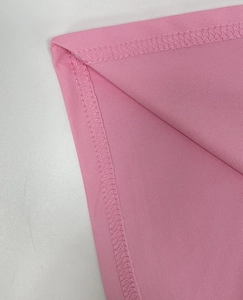 Close-up of pink knit fabric with professional double-needle stitching and fine texture
