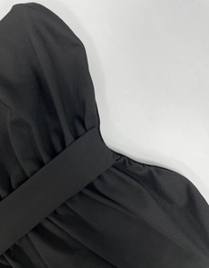 Detail of a black bodycon dress featuring waist pleats and a matching wide sash belt