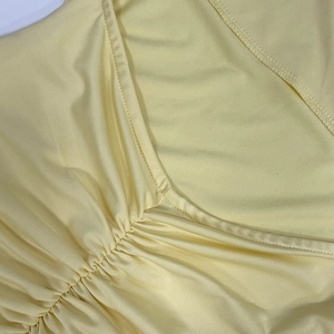Close-up of V-neckline with ruched detailing on a yellow slim-fit knit dress