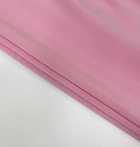 Detailed close-up of soft pink ribbed knit fabric with elastic texture on the dress