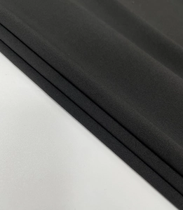 Close-up of black ruched fabric texture with elegant draping and high-density weave detail